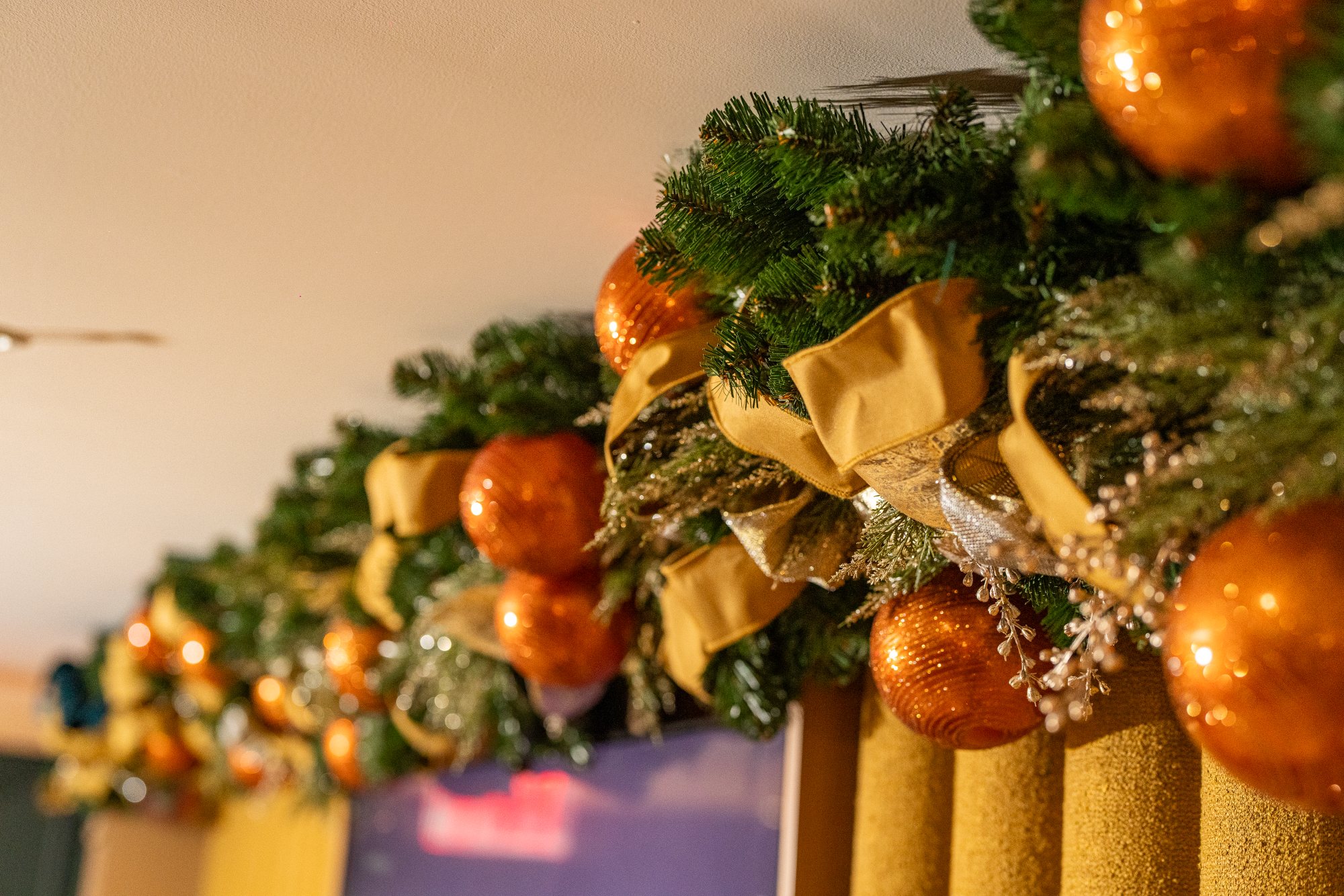 Mantel garland detail with polished copper ornaments, teal velvet ribbon curls, and jeweled gold trim